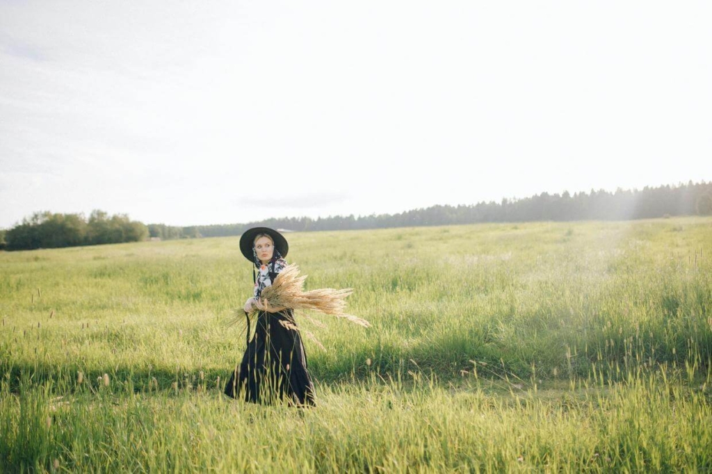 woman carrying wheat in a grass field landscape