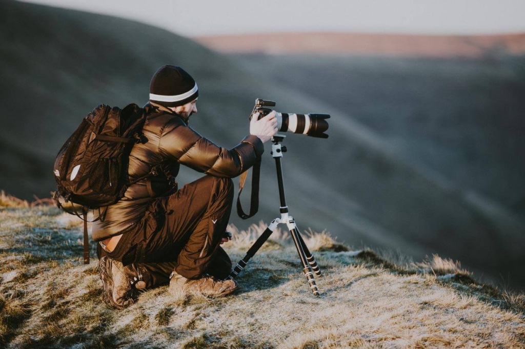 Landscape photographer mounting a tripod on top of a hill